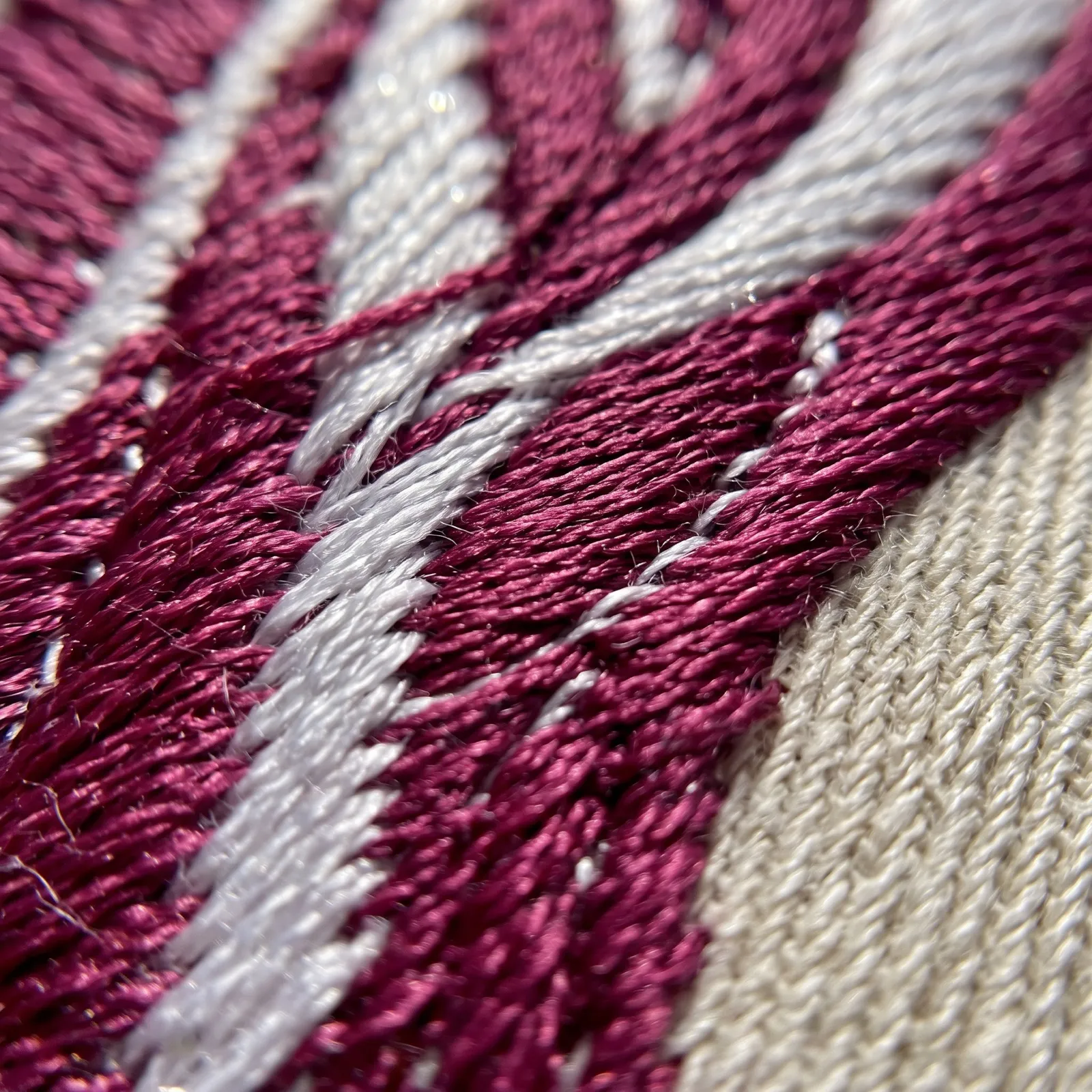Puntadas de bordado en hilo magenta y blanco, de muy cerca