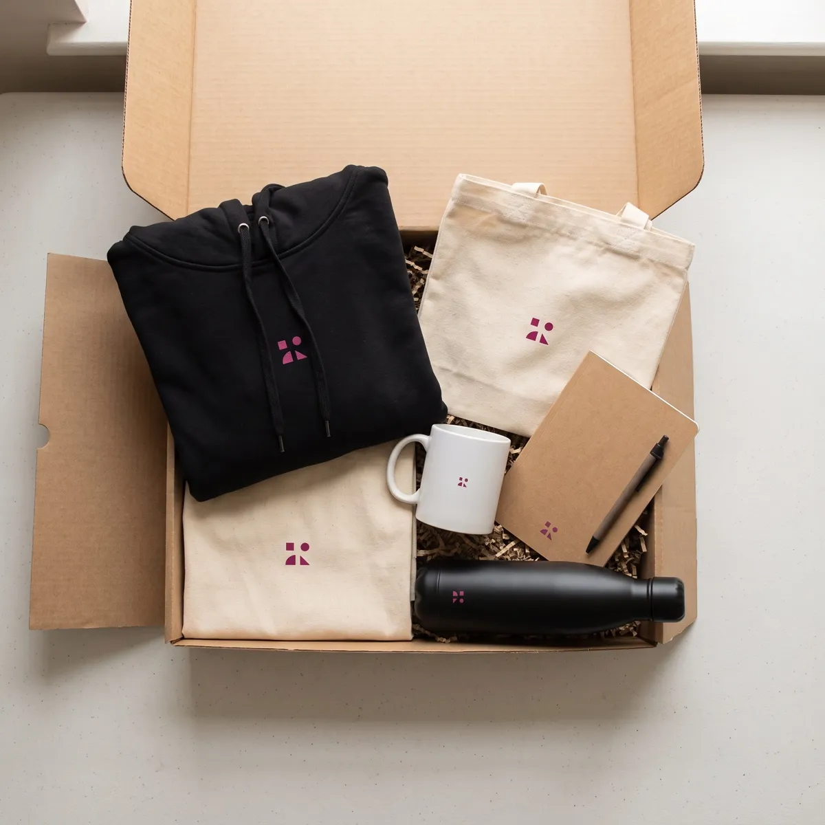 Kit de bienvenida en una caja de cartón: sudadera, taza, libreta, botella y bolsa